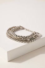 Layered bracelet with metal beads and chain detail.